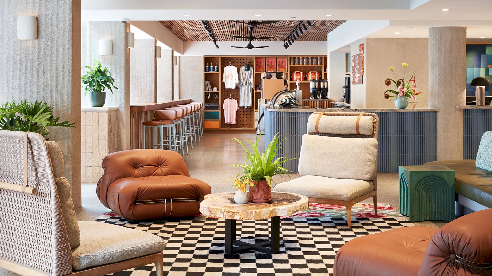 This image shows a stylish lounge area with modern furniture, plants, a checkered rug, and a bar in the background, creating a cozy ambiance.