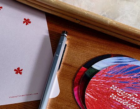 A pen, circular flyers, a notecard with "Stop and Smell the Flowers" text, and a tray on a wooden surface.