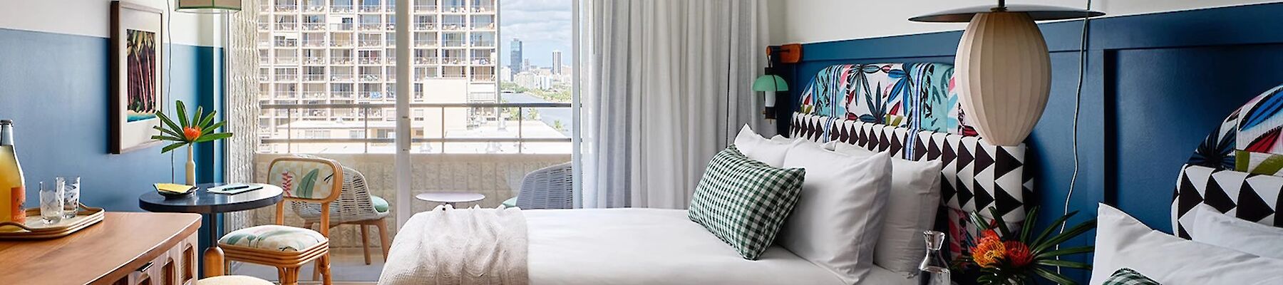 A cozy hotel room with two beds, a balcony, vibrant decor, and city view. end of sentence.