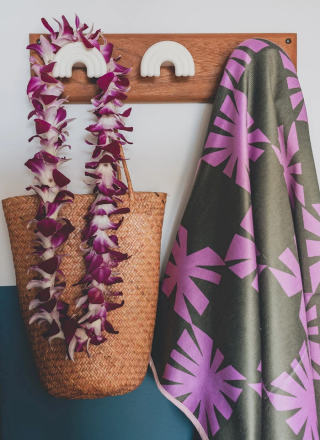 Un porte-manteau d&eacute;coratif orn&eacute; de motifs color&eacute;s, d'un collier de fleurs, d'une chemise tropicale et d'un sac en osier.