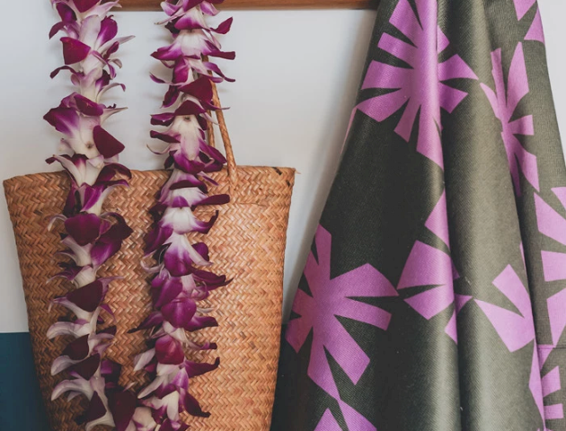 A decorative coat rack featuring colorful decor and a flower necklace hanging with a tropical shirt hanging and a woven bag