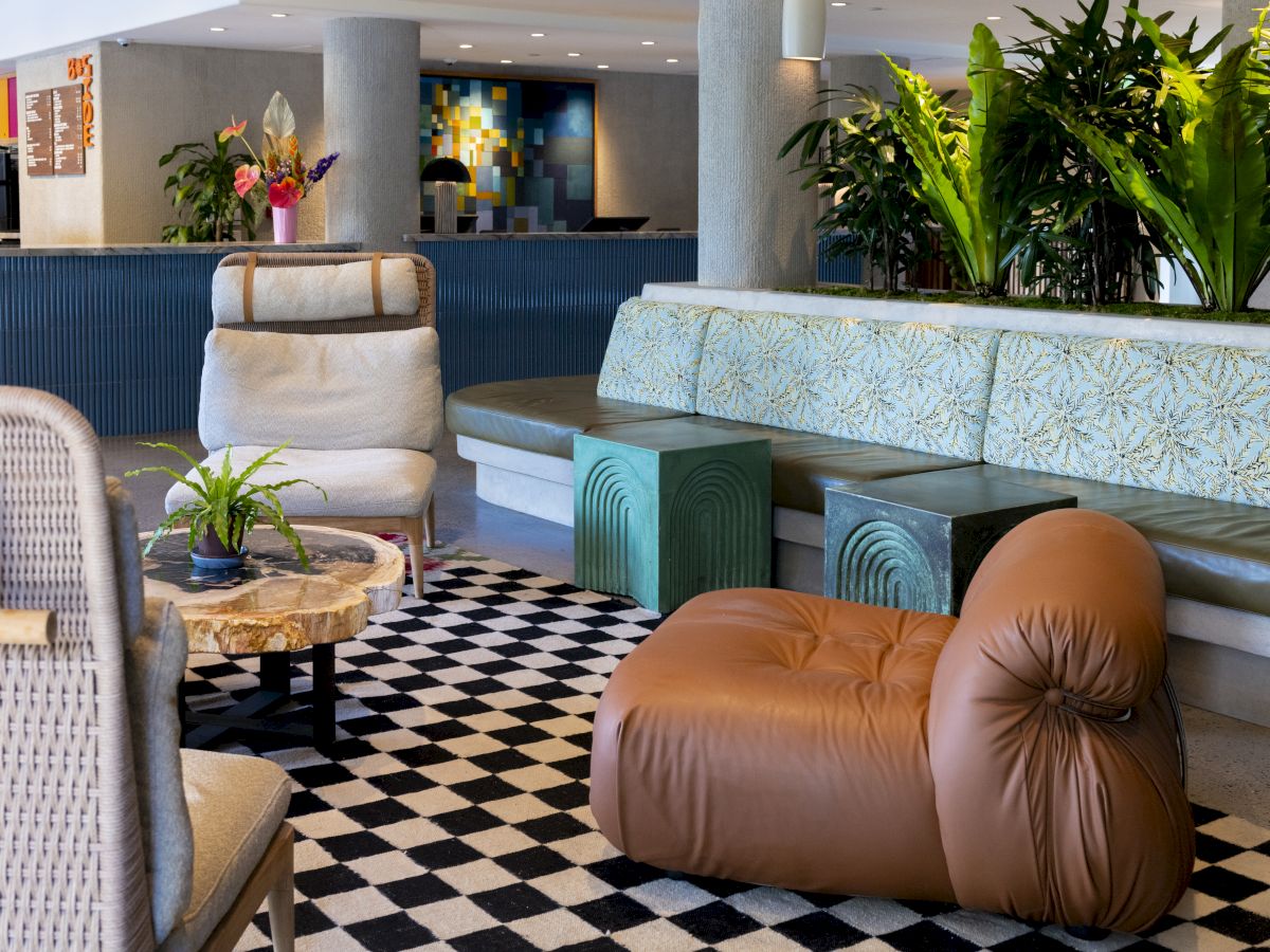 The image shows a modern lounge with stylish chairs, a patterned floor, plants, and a table, creating a cozy and inviting atmosphere.