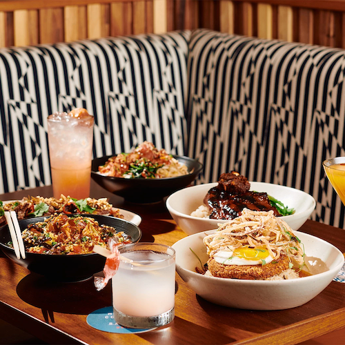 A dining booth with various plated dishes and drinks, featuring a colorful and appetizing spread of food and beverages on a wooden table.