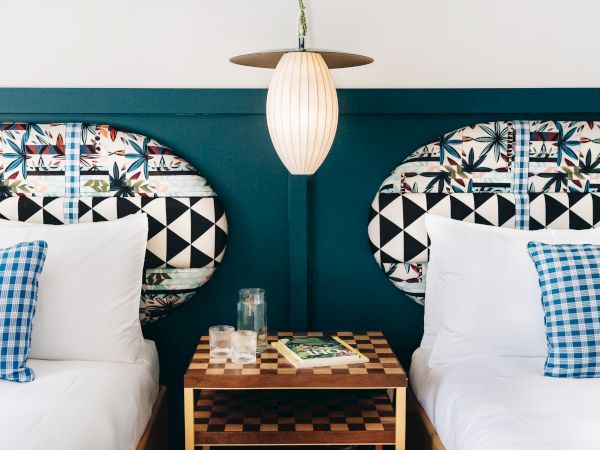 A cozy booth seating area with patterned cushions, a hanging pendant lamp, and a small table with glasses and a magazine.