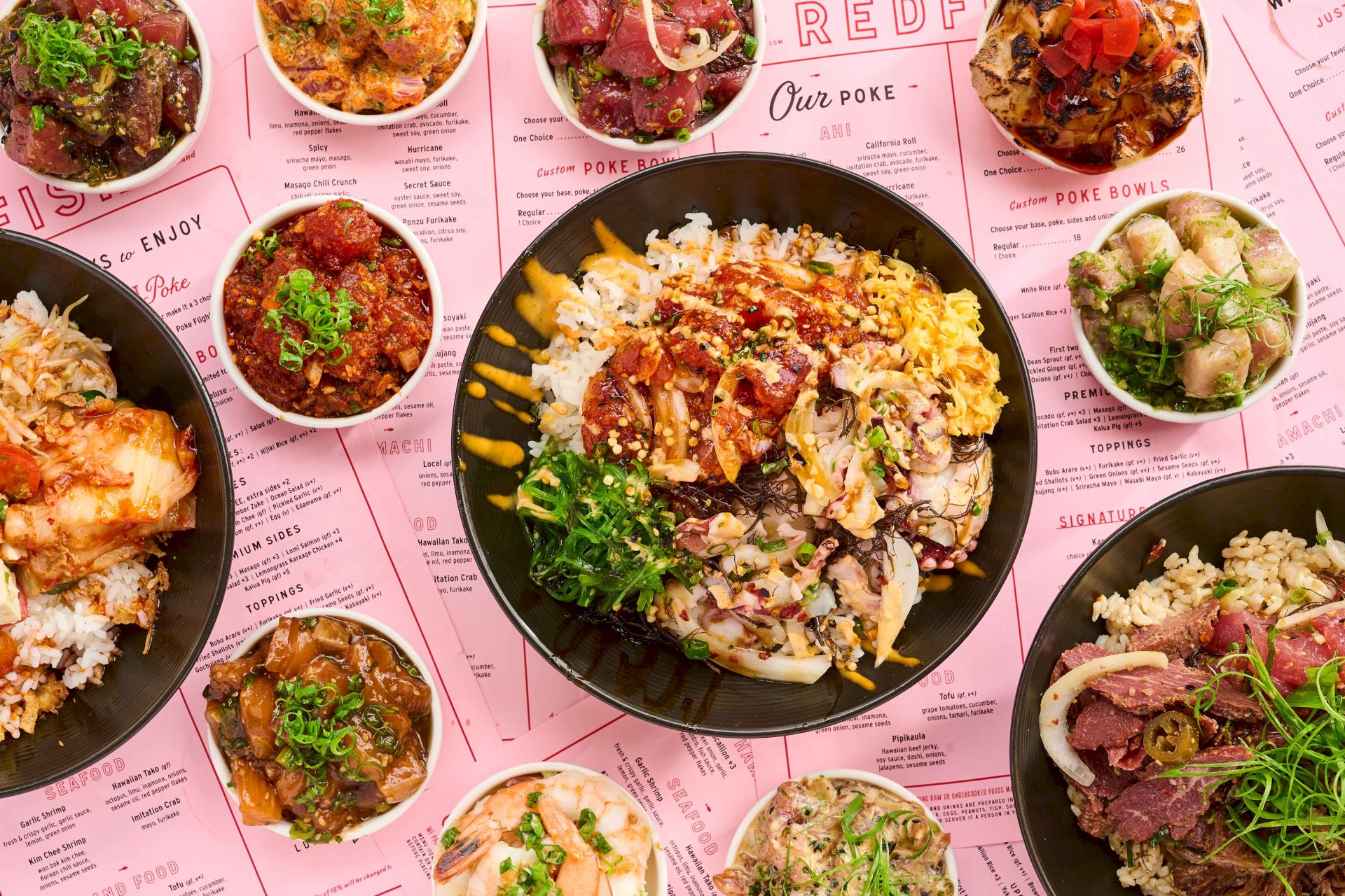 Colorful custom poke bowls and toppings shown on a printed menu, with a large central bowl surrounded by smaller bowls.